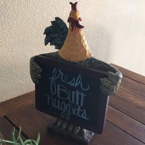 Rooster statue holding a chalkboard sign.